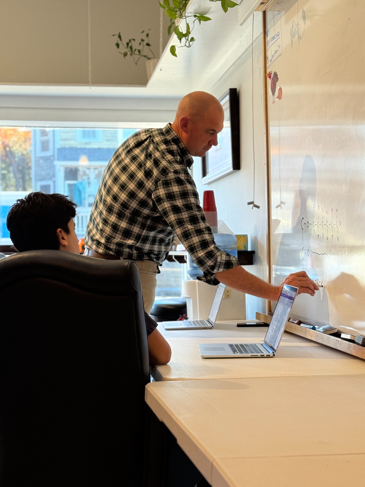 An instructor working one-on-one with a student at the whiteboard